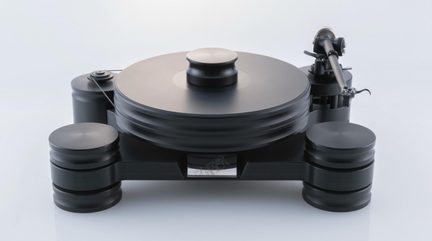 Prato de vinil preto fosco em metal usinado, vista frontal, bandeja circular espessa com peso central, braço de leitura cinza à direita, correia de acionamento à esquerda, apoiado por três pés cilíndricos empilhados