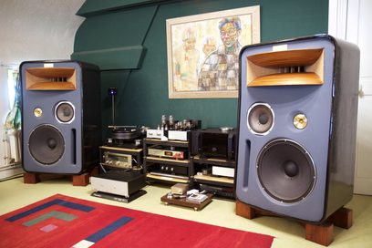 To vintage højttalere i marineblå og to vintage hi-fi-forstærkere i træ, med et abstrakt maleri på væggen