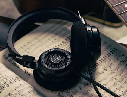Auriculares con cable negros de tipo abierto, de plástico y espuma, vista desde arriba sobre partituras musicales