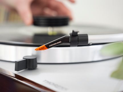 Juoda vinilo plokštelė, raudona skaitytuvė, balta foninė danga, artimas viršutinis vaizdas, sufokusuotas į skaitytuvę