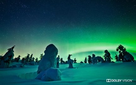 Grønt nordlys på en stjerneklar himmel over snedækkede klippeformationer i søjleform