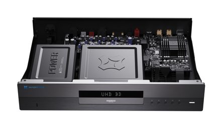 Sort diskafspiller i børstet aluminium, set ovenfra i trekvart vinkel forfra med låget fjernet, hvilket afslører to interne metalafskærmninger og printkortet, frontpanel med digitalt display “UHD BD”