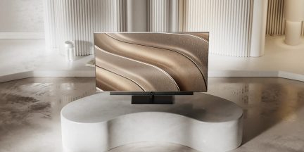 Schwarzer Flachbildfernseher auf zentralem Standfuß, auf einem weißen Couchtisch in einem modernen Wohnzimmer platziert