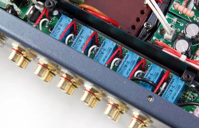 Vista interna di un amplificatore integrato hi-fi PrimaLuna Evo 300 nero che mostra condensatori blu e valvole rosse