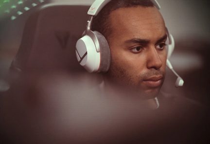 Cuffie gaming bianche con microfono ad asta indossate da un giocatore concentrato davanti al suo schermo