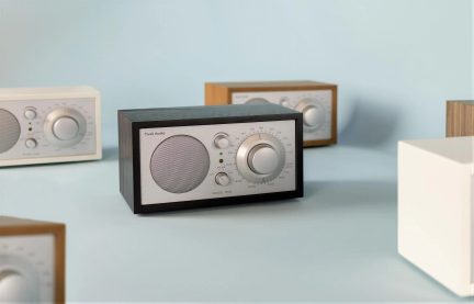 Radio da tavolo in legno nero, pannello frontale in alluminio, altoparlante sinistro, grande pulsante a destra, vista da tre quarti anteriore