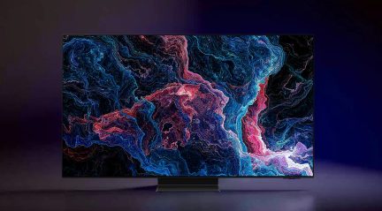 Pantalla rectangular negra con bordes finos, soporte central rectangular, muestra un diseño abstracto multicolor