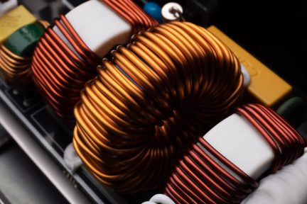 Bobina di induttanza toroidale in rame su circuito elettronico, primo piano con componenti gialli e bianchi