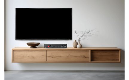 Sort vægmonteret fladskærms-tv, svævende møbel i lyst træ med skål, sort forstærker med rød skærm, keramiske vaser, frontvisning