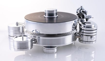 Prata de toca-discos em metal polido com prato circular espesso encimado por um disco de vinil preto, braço de leitura articulado e blocos cilíndricos laterais estriados, vista de três quartos frontal