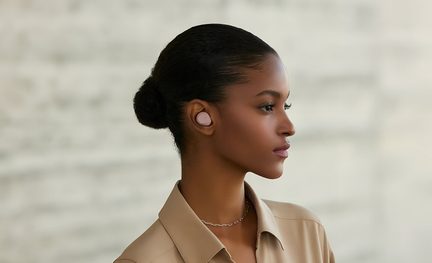 Close-up van een matroze, afgeronde in-ear oordop van kunststof in het rechterprofiel, gedragen door een vrouw voor een vage achtergrond