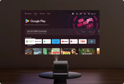 Proiettore rettangolare su tavolo rotondo, schermo a parete che mostra l'interfaccia di Google Play con icone di applicazioni e film