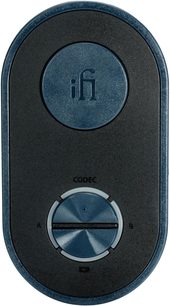 Drahtloser iFi Audio UP Travel Sender in schwarzem und blauem Metallic-Kunststoff mit matter Oberfläche, ovales Gehäuse in Frontansicht, mit großem rundem, logobedrucktem Knopf oben, drehbarem A/B-Codec-Wähler und LED unten