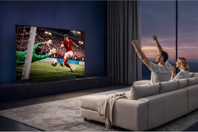 Širokoúhlý plochý televizor Samsung TMR65R85H s tenkým rámečkem zobrazující fotbalový zápas v moderním obývacím pokoji