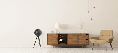 Trådløs tilsluttet Elipson Planet W35+ sort højttaler, lampe, lænestol og sofa i beige nuancer i en minimalistisk og afdæmpet stue