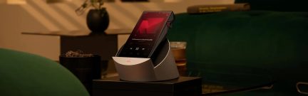 Lettore audio ad alta risoluzione nero su base di ricarica grigia, schermo touch con interfaccia musicale rossa