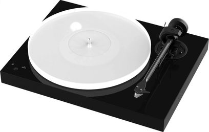 Pro-Ject X1 pladespiller i piano sort, set oppefra, hvid rund pladespiller, sort tonarm, på en rektangulær, blanklakeret sort base
