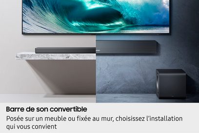 Soundbar Samsung HW-QS710F 2025 nera con griglia metallica, vista frontale, metà appoggiata metà a parete, subwoofer nero