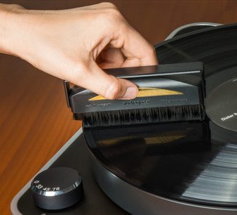 Mantendo uma escova antiestática Audioquest de fibra de carbono em um toca-discos de vinil, vista aproximada de cima