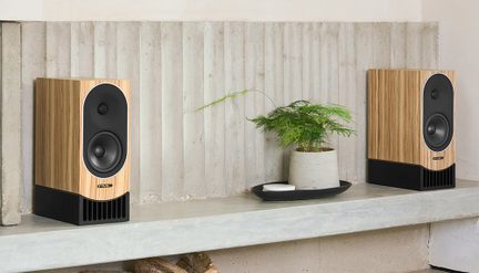 Ljus- och mörkbruna PMC-stereohögtalare i bokhylleformat, modern design på betonghylla med dekorativ växt