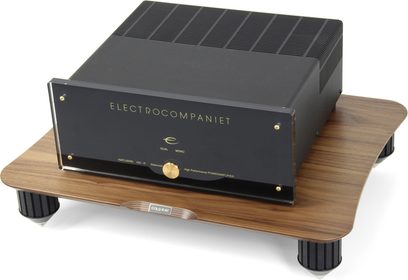 Electrocompaniet melns audio pastiprinātājs, priekšējais panelis ar zeltītiem pogām, novietots uz gaiša koka paliktņa