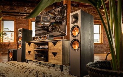 Système audio home cinéma en bois avec enceintes, écran TV affichant une voiture et éclairage orange intégré