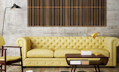 Gele mosterdkleurige 3-zitsbank in Chesterfield-stijl, gouden tafellamp, houten salontafel, wandpaneel van verticale houten latten