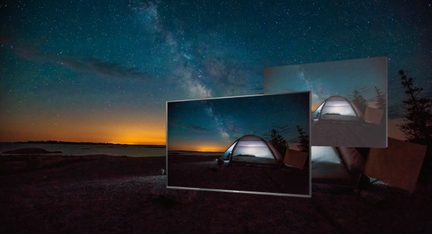 Três tendas transparentes iluminadas por dentro em um terreno rochoso sob um céu noturno estrelado com a Via Láctea