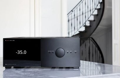 Melnas Anthem STR integrētais stereo pastiprinātājs, skats no priekšpuses, novietots uz marmora virsmas, ar kāpnēm fonā