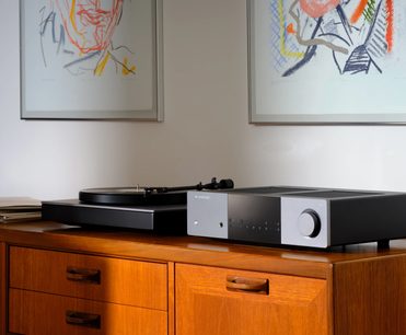 Cambridge Audio EXA100 integrált sztereó hi-fi erősítő, előlről látható, kör alakú gombbal, sima felülettel, fapolcon