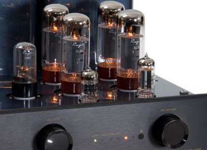 Ön üç çeyrek yakın çekim görüntüsü, siyah fırçalanmış metal şasiye sahip Cayin CS-100A EL34 tüp entegre stereo amplifikatör, ön panelinde iki büyük dairesel düğme ve LED göstergeler bulunan, üst kısmında silindirik cam EL34 ve 6SN7 akkor tüpler sıralanmış