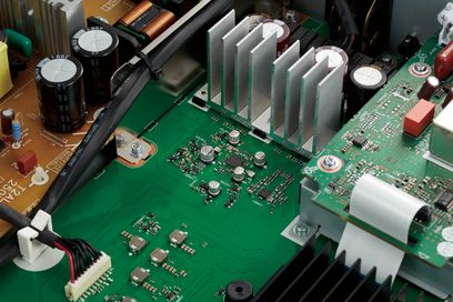 Zielona płytka drukowana z komponentami elektronicznymi, aluminiowymi radiatorami i białymi złączami, zbliżenie