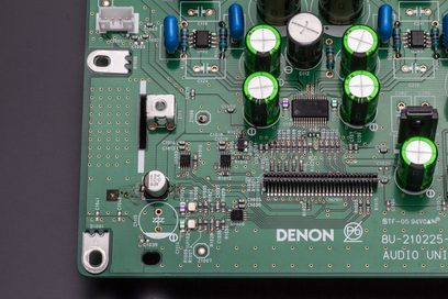 Zielona płytka drukowana z komponentami elektronicznymi, niebieskimi cylindrycznymi kondensatorami i srebrnymi potencjometrami obrotowymi