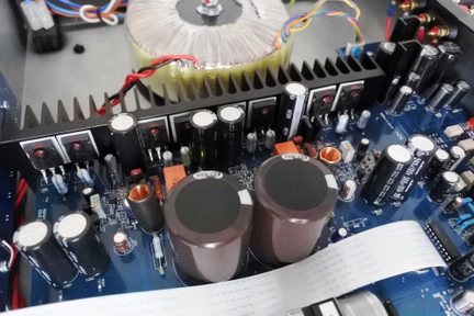 Blå printplade med mange elektroniske komponenter: kondensatorer, modstande, spoler og ledninger i forskellige farver