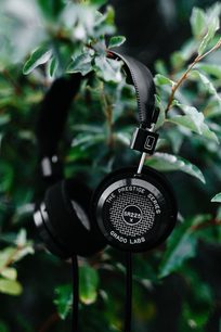 Åbent hi-fi hovedsæt Grado SR225x lagt på grønne blade, set fra siden, højre ørekop i forgrunden