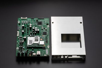 Grønt kretskort med elektroniske komponenter og åpent metallkabinett som inneholder en LCD-skjerm, toppvisning