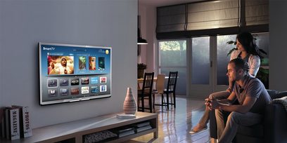 Philips 40PFL5507 tv der viser en SmartTV-grænseflade, et par sidder i en sofa og ser på det i en stue