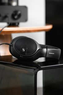 Μαύρα ακουστικά Sennheiser HD 560S, τριτεταρτοκυκλική όψη, τοποθετημένα σε ανοιχτόχρωμη ξύλινη βάση, με μαύρο καλώδιο