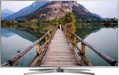 Panasonic TX-75FX780 fladskærms-TV, der viser en træbro over en sø omgivet af bjerge med skov