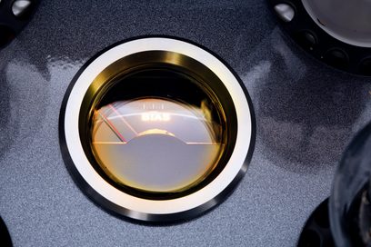 Primer plano, vista superior, del vúmetro circular «BIAS» con cristal ámbar y borde metálico plateado, integrado en el chasis metálico negro satinado del Cayin CS-805A