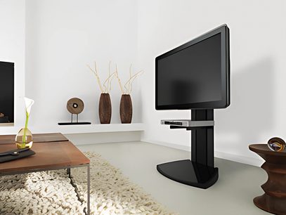 Sort TV-møbel på fødder med fladskærm, i en moderne stue med minimalistisk indretning og hvide klinker på gulvet