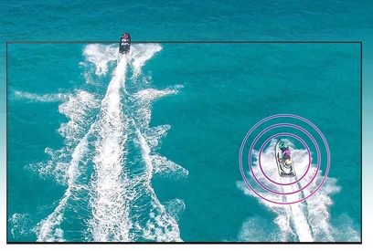 Jet-ski brázdící bílé stopy v tyrkysové vodě, pohled z ponoření skrz růžový fluorescenční kruh
