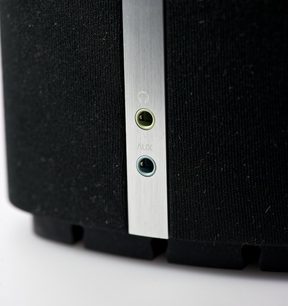 Detalje af en sort Bowers & Wilkins MM-1 højttaler med børstet aluminiumsstik til AUX-indgang på siden