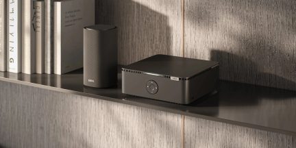 Loewe-højttaler og audiokabinet i antracitgrå på hylde, set skråt forfra med bøger i baggrunden