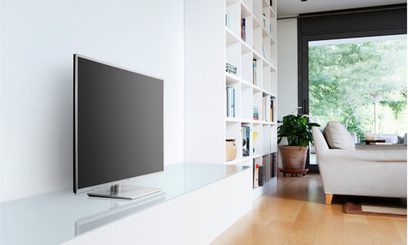 Panasonic TX-L50ET60E-tv på hvidt møbel i moderne interiør med store vinduer og grå sofa