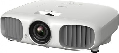 Bílý videoprojektor Epson EH-TW6000W, pohled zepředu mírně ze strany, objektiv vlevo, ventilační mřížky vpravo