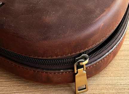 Близък план на ципа на кафяв кръгъл калъф със златист плъзгач