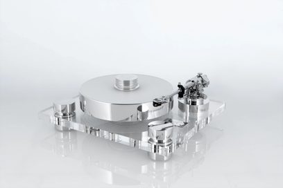 Transrotor Bellini RB880 hi-fi pladespiller i sølvfarvet poleret metal, placeret på en rektangulær base af transparent akryl, tyk cirkulær pladetallerken med pladevægter, sideplaceret tonearm og matchende cylindriske fødder, set fra trekvart forfra