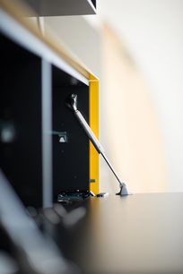 Gul og grå lodret støvsuger, tæt sidevinklet, mundstykke og teleskopisk aluminiumsrør, mod en hvid væg
