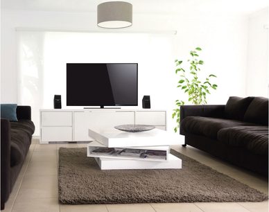 Moderne stue med mørkebrune lædersofaer, hvidt sofabord, hvid TV-møbel, fladskærms-TV og grønne planter